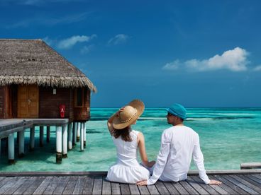 Man and woman sitting on dock overlooking ocean